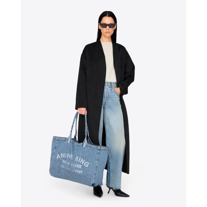 Cabas Leo Denim Tote Anine Bing en toile de coton bleu délavé, porté à la main.
