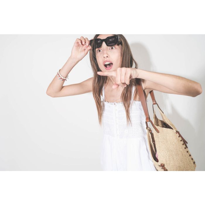 Lunettes de soleil monture noire logo doré AB sur les branches Indio AB Anine Bing. Portées avec une combishort Dylan Marant Etoile et un panier en osier naturel Tampa Isabel Marant. Bracelets Isabel Marant. 