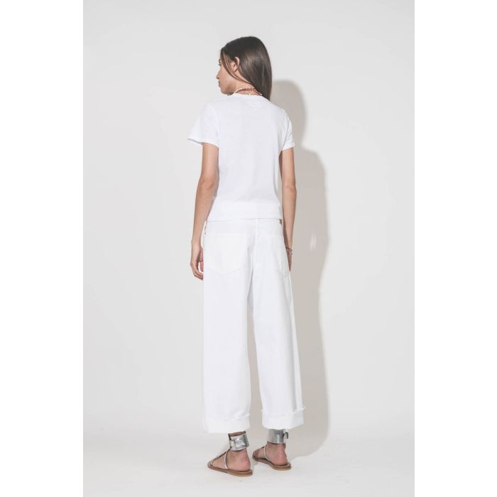 Jean large taille basse en toile blanche lavée Georgia Denimist. Porté de dos avec un tee-shirt Little blanc The Great et des sandales Caravelle en cuir argent K.Jacques Saint-Tropez. Bijoux Isabel Marant.