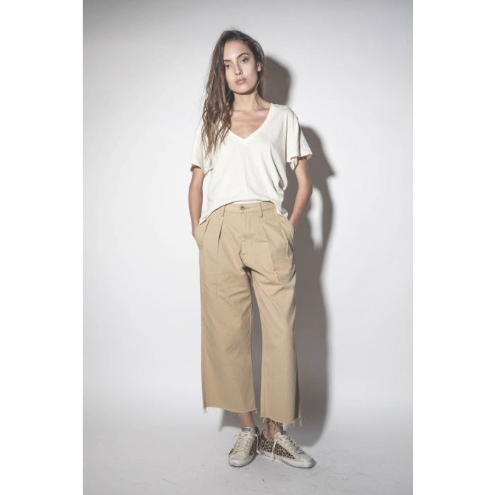 Pantalon large à pinces en toile de coton beige Chino Denimist. Porté les mains dans les poches.