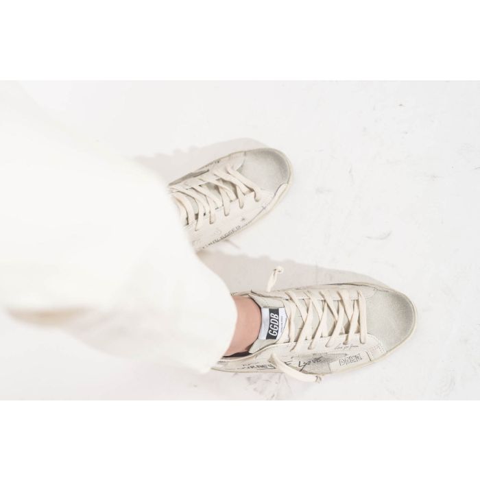 Sneakers en cuir blanc Graffiti écritures et dessins noirs arrière en cuir argent Golden Goose femme. Edition limitée. Portées avec un jean Boy Straight écru stretch R13.