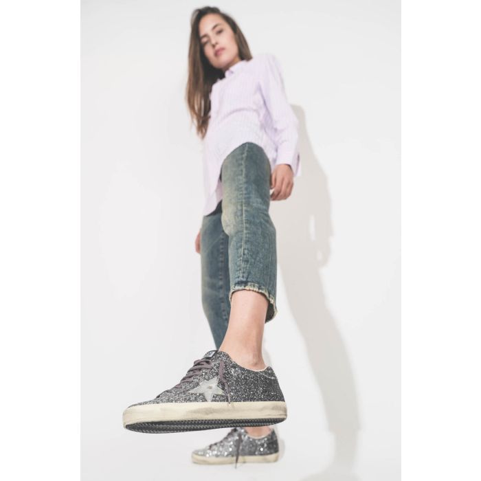 Sneakers entièrement recouvertes de paillettes argentées et noires, étoile en cuir lisse tague écritures noires sur la semelle droite beige "LOVE You To The Star And Back"  Super-star Golden Goose femme. porté avec un jean Boy Straight bleu R13 et une che