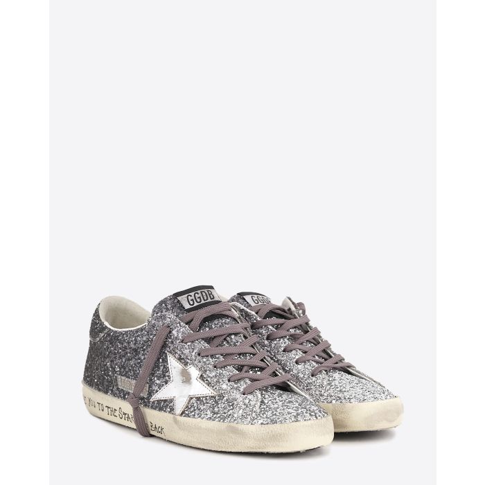 Sneakers entièrement recouvertes de paillettes argentées et noires, étoile en cuir lisse tague écritures noires su la semelle beige "L????VE You To The Star And Back"  Super-star Golden Goose femme. Face.