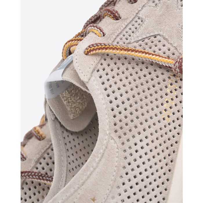 Sneakers Super-Star Golden Goose en daim crème ajouré étoile ton sur ton. Détail des matière et lacets multicolores.