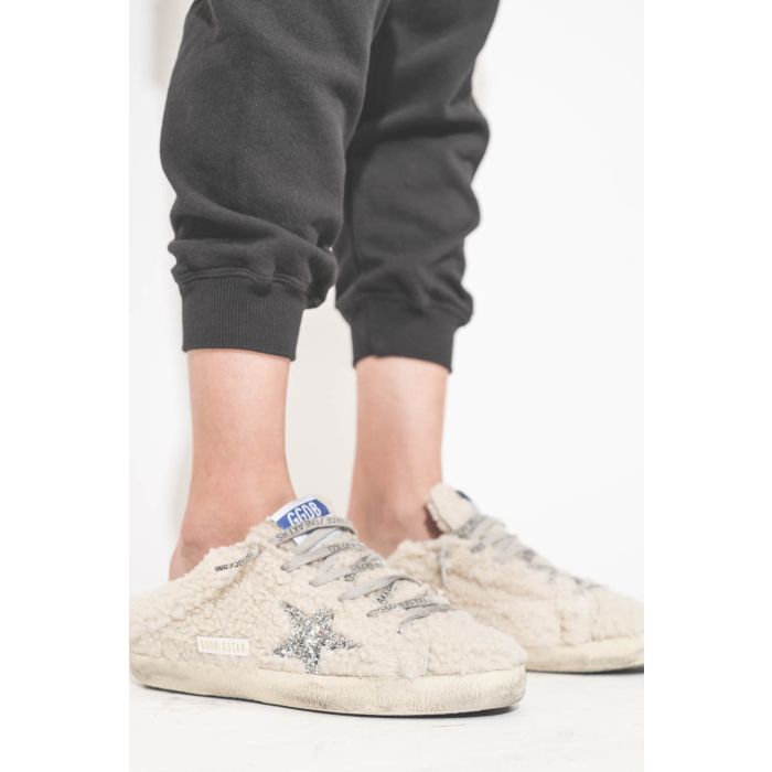 Sneakers sabot en fourrure de mouton retournée écru étoile à paillettes argentées 10757 Super-Star Sabot Golden Goose femme. Portées avec un bas de jogging Cropped noir The Great.