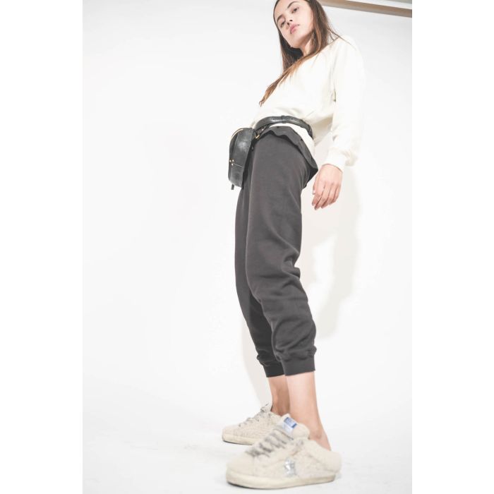 Sneakers sabot en fourrure de mouton retournée écru étoile à paillettes argentées 10757 Super-Star Sabot Golden Goose femme. Portées de profil avec un sweat-shirt écru Shrunken et un bas de jogging Cropped noir The Great. Sac banane en cuir noir Lino Jérô