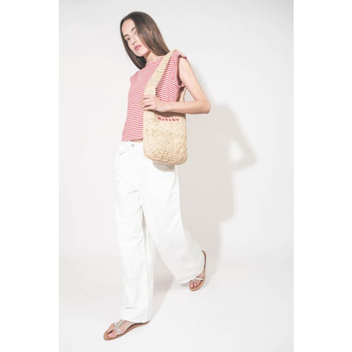 Jean large à pinces taille basse en toile blanche Candy Twill Haikure. Porté de profil avec un tee-shirt rayé rouge et blanc The Great et un panier en osier Isabel Marant. 