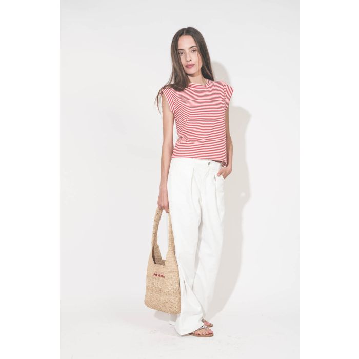 Jean large à pinces taille basse en toile blanche Candy Twill Haikure. Porté de face avec un tee-shirt rayé rouge et blanc The Great. Un panier en osier Isabel Marant et des sandales en cuir argent K.Jacques St Tropez.