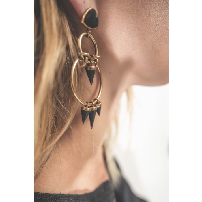 Boucles d'oreilles Be With You Isabel Marant à anneaux et pendentifs en laiton doré et résine noire. Portées de profil.