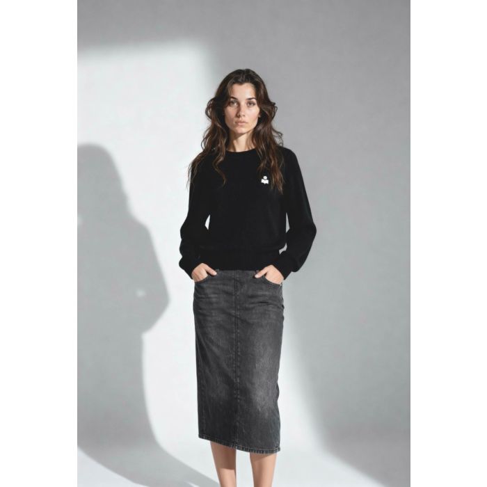 Pull Abelle Isabel Marant Étoile en coton et laine noir, logo brodé en argent sur la poitrine. Porté de face avec une jupe en denim gris. 
