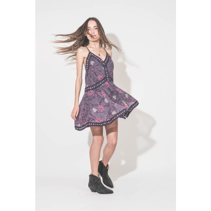 Robe au dessus du genoux fines bretelles en voile de coton imprimé fleurs violettes doublée Daniella Isabel Marant Etoile. Portée de profil avec des boots en cuir suédé noir délavé Dewina Isabel Marant et un collier tibétain Sharing. 