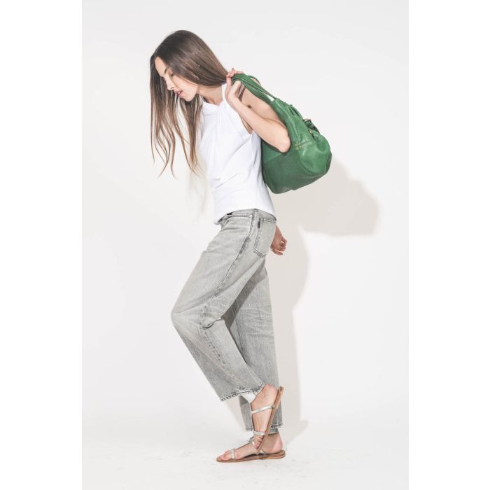 Tee-shirt sans manches noué sur le devant de l'épaule asymétrique en jersey blanc Nayda Marant Etoile. Porté avec une jean large gris Betty Haikure et des sandales plates en cuir argent Caravelle K.Jacques St-Tropez. Sac cabas porté main en cuir vert gazo