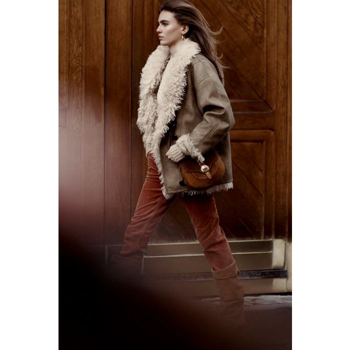 Sac Altay Small Isabel Marant en cuir suédé cognac. Bandoulière longue et patte en cuir tressé naturel. Porté épaule en camaïeux de beige. 