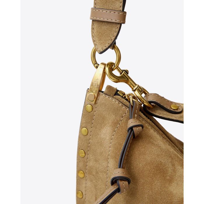 Sac Oskan Soft Zip Isabel Marant en cuir suédé taupe et clouté. Bandoulière courte pour un porté main ou épaule et une bandoulière longue pour un porté épaule ou croisé. Détail du mousqueton et des anneaux en métal doré gravé "Isabel Marant"