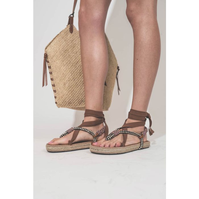 Sandales entre-doigts en cordes tressées multicolores beige et ruban beige à lacer autour des chevilles Gypsa Isabel Marant. Portées de profil avec un panier en osier naturel et cognac Tampa Isabel Marant.