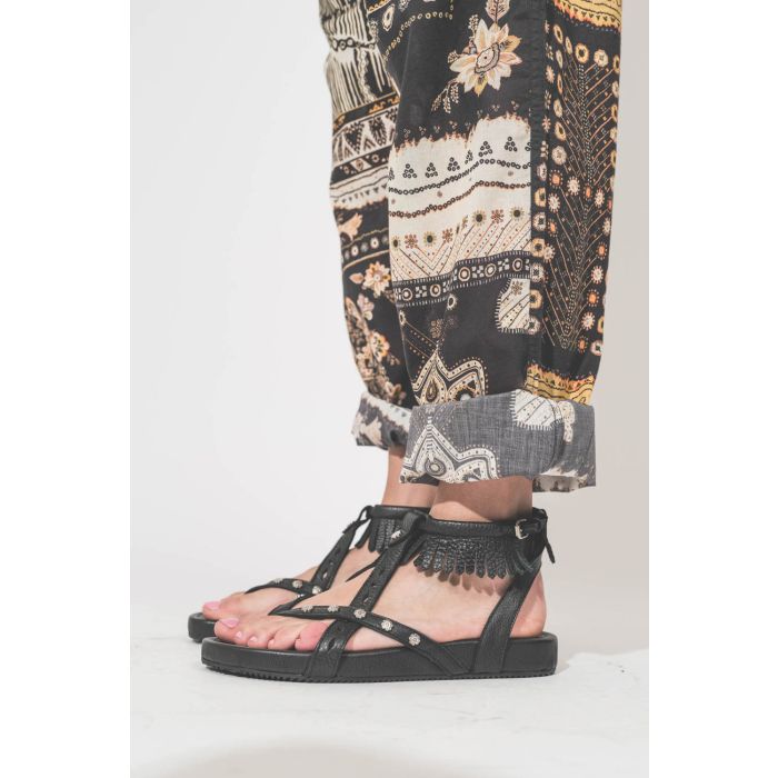 Sandales en cuir noir clouté bride à franges autour de la cheville Silya Isabel Marant. Porté de profil avec un pantalon en voile de coton imprimé Fedora Marant Etoile.