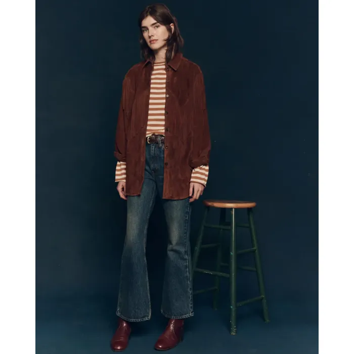 Jean évasé en denim bleu Penny The Great. Porté avec une veste en cuir suédé à franges marron.