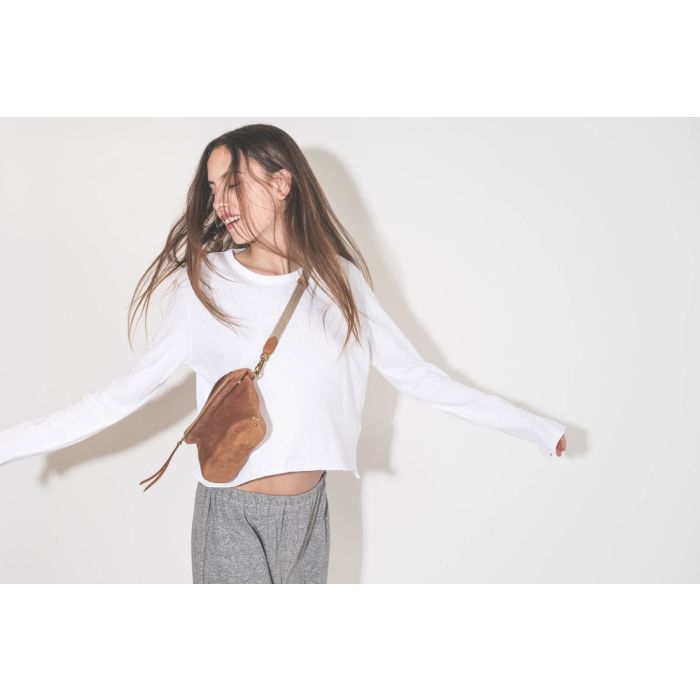 Bandoulière sangle amovible écru finition cuir chêne Jérôme Dreyfuss. Porté avec une pochette en cuir suédé caramel Lucky Jérôme Dreyfuss. Tee-shirt manches longues court blanc The Great et pantalon sarouel en jersey gris chiné The Great. 