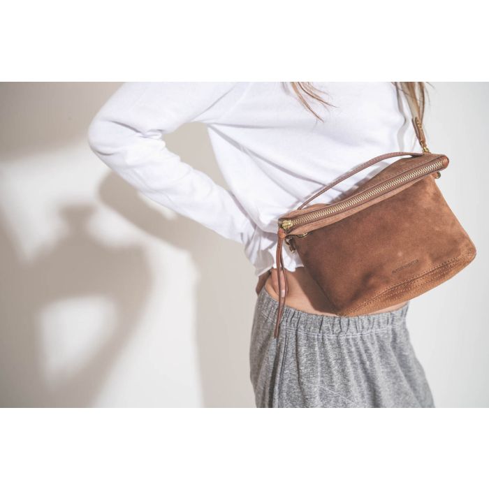 Bandoulière sangle amovible écru finition cuir chêne Jérôme Dreyfuss. Porté avec une pochette en cuir suédé caramel Lucky Jérôme Dreyfuss. Tee-shirt manches longues court blanc The Great et pantalon sarouel en jersey gris chiné The Great. Détail de la poc