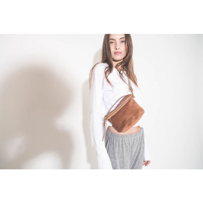Bandoulière sangle amovible écru finition cuir chêne Jérôme Dreyfuss. Porté de profil avec une pochette en cuir suédé caramel Lucky Jérôme Dreyfuss. Tee-shirt manches longues court blanc The Great et pantalon sarouel en jersey gris chiné The Great. 