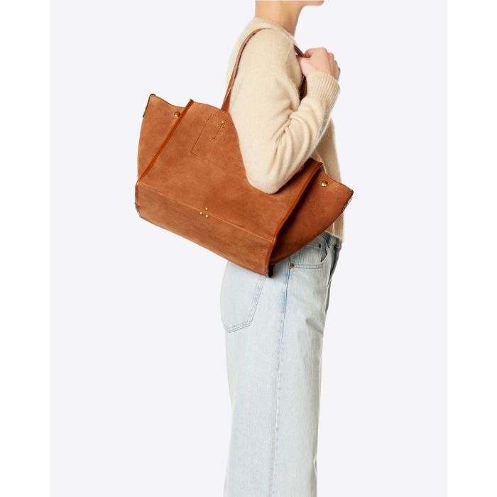 Sac cabas Léon M Jérôme Dreyfuss en cuir suédé caramel porté à l'épaule.