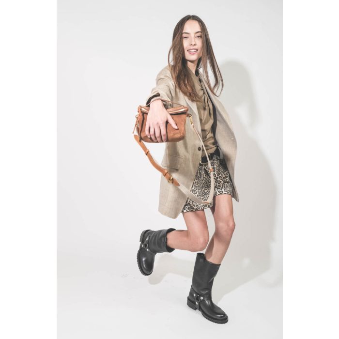 Pochette en cuir suédé caramel Lucky Jérôme Dreyfuss portée main avec une bandoulière sangle large écru Jérôme Dreyfuss. Alyssa porte une veste Ragged Oversized beige en lin R13, un tee-shirt Nayda kaki Marant Etoile et un short en toile léopard Pocket R1