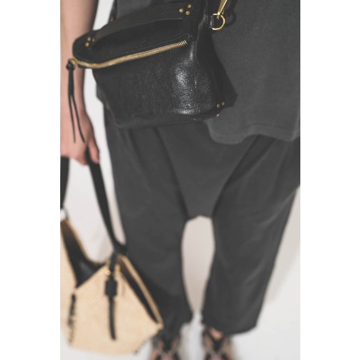 Pochette en cuir de chèvre noir grainé portée crossbody avec une bandoulière sangle large noire Jérôme Dreyfuss. Tee-shirt manches courtes Boxy Crew et pantalon sarouel en jersey noir délavé The Great. Sandales en cordes tressées et ruban noir Gypsa Isabe