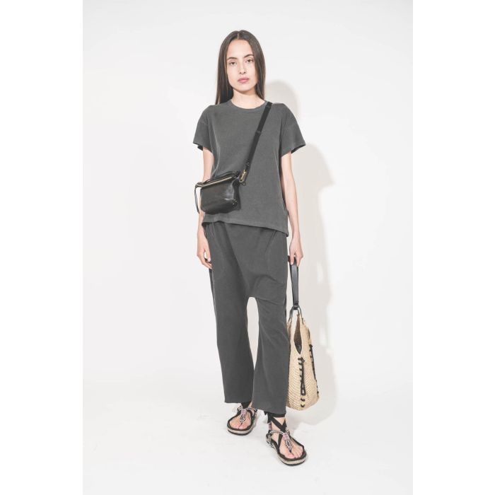 Pochette en cuir de chèvre noir grainé portée crossbody avec une bandoulière sangle large noire Jérôme Dreyfuss. Tee-shirt manches courtes Boxy Crew et pantalon sarouel en jersey noir délavé The Great. Sandales en cordes tressées et ruban noir Gypsa Isabe