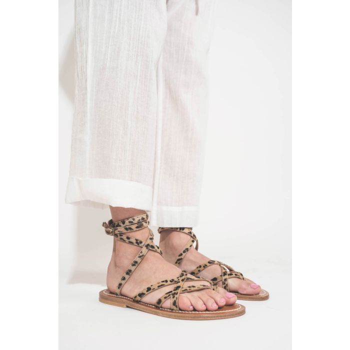 Sandales plates avec brides Zenobie K.Jacques St-Tropez en cuir "pony" léopard. Porté de profil avec un pantalon en voile de coton blanc The Great.
