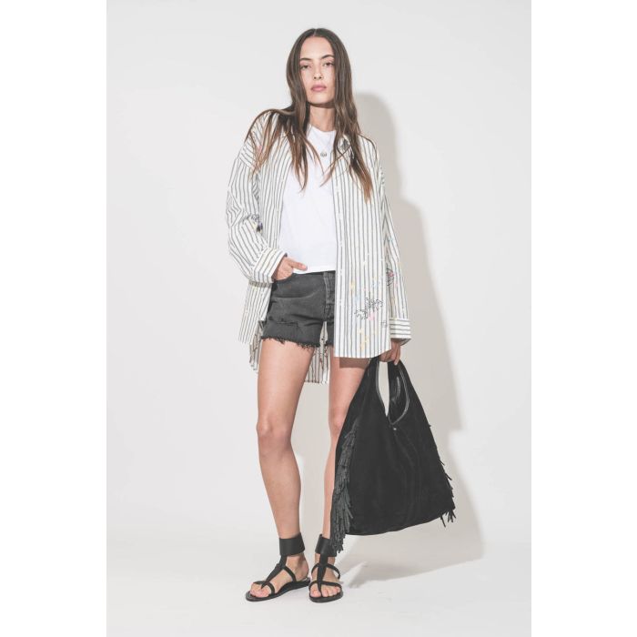 Sandales plates bride large à la cheville en cuir noir ébène Caravelle K.Jacques St-Tropez. Portées de profil avec une chemise oversized graffiti R13, un tee-shirt blanc The Great, un short en jean noir Mikuta et un sac à franges Paco Jérôme Dreyfuss. 