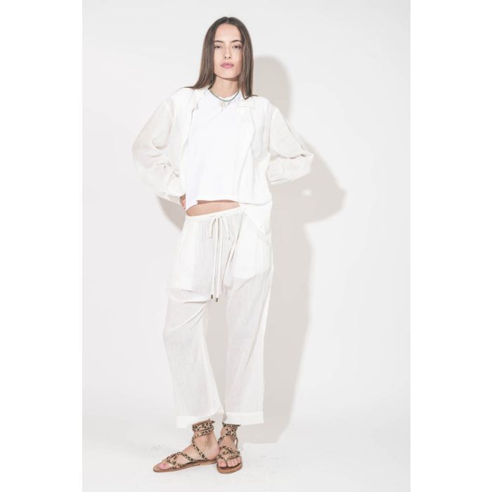 Sandales plates avec brides Zenobie K.Jacques St-Tropez en cuir "pony" léopard. Porté de face avec un chemise en voile de coton blanc et un pantalon assorti en voile de coton blanc The Great. Tee-shirt sans manches blanc The Peak Shoulder The Great.