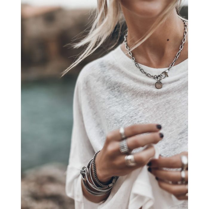 Collier ras du cou chaine avec médaille gravée Me en argent Mikuta. Porté sur un tee-shirt en lin blanc.