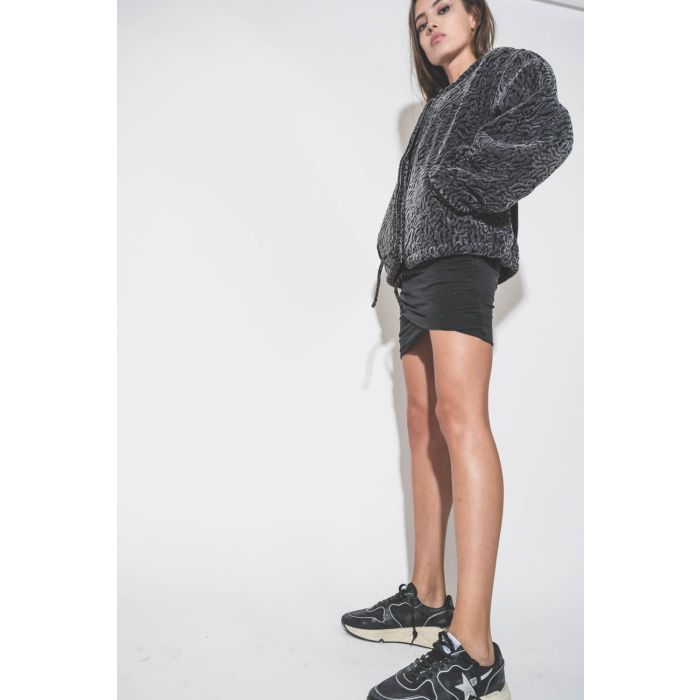 Mini-jupe drapée en jersey noir Mikuta. Porté avec un blouson bomber en velours.