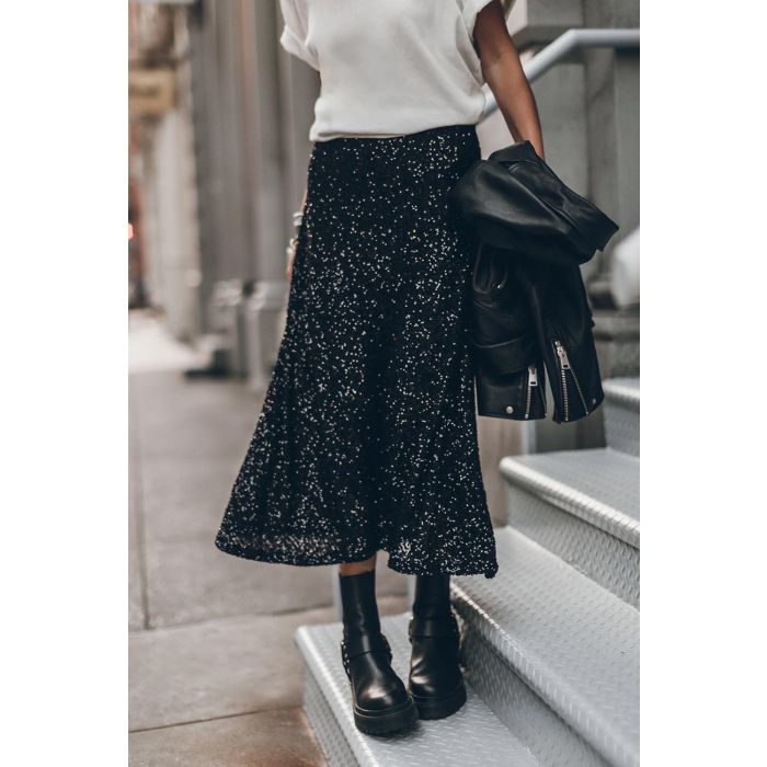 Jupe midi évasée à paillettes noires Mikuta. Portée avec un tee-shirt blanc.