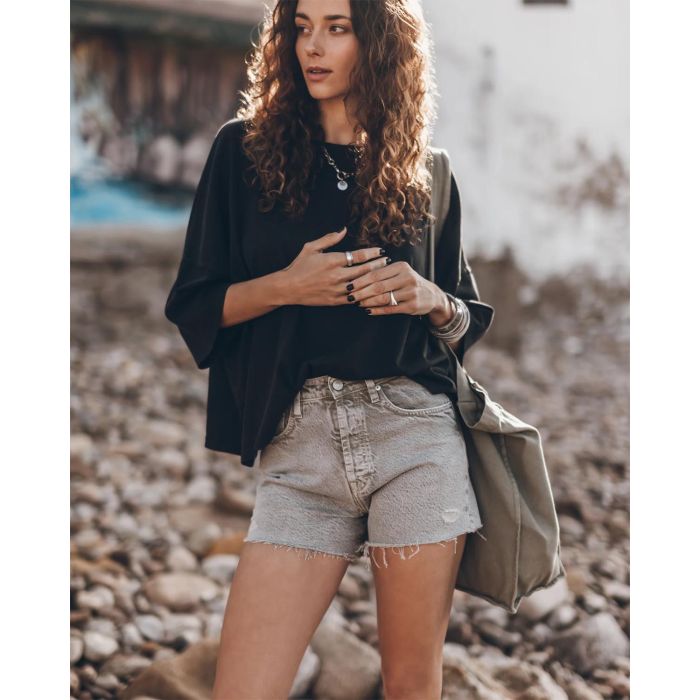 Tee-shirt manches courte épaule basse en coton noir oversize Mikuta. Porté avec un short en jean kaki Mikuta et des bijoux en argent Mikuta.  