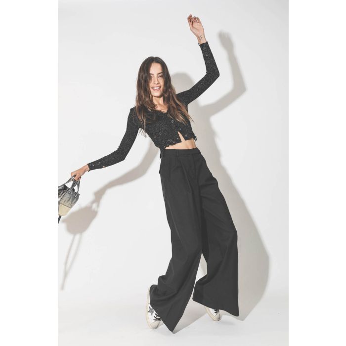 Pantalon taille haute à pinces en laine froide noire Maison Flaneur. Porté avec un gilet court en lurex.