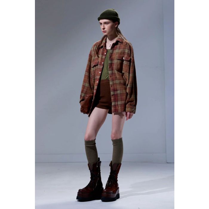 Chemise oversize Boyfriend Shirt R13 en flanelle à carreaux rouges et marron, portée ouverte sur un tee-shirt. 