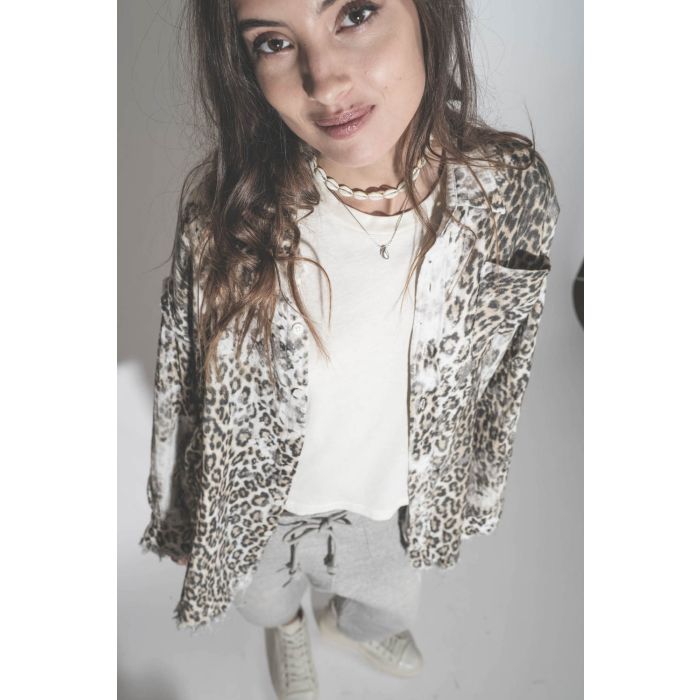 Chemise oversize en coton imprimé léopard délavé bord franc Shredded léopard R13. Porté avec un collier coquillage. 