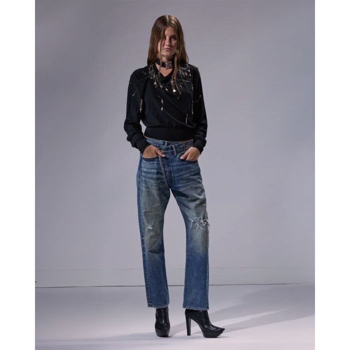 Jean crossover R13 en denim bleu déchiré Léo Blue, porté de face avec un pull noir R13.