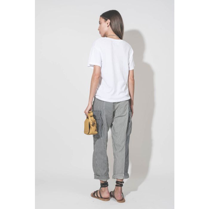 Pantalon oversize à rayures bleues Cargo Railroad R13. Porté de dos avec un tee-shirt blanc col V The Great, des sandales plates en cuir noir Zenobie K.Jacques Saint-Tropez et un sac Pepito S jaune Mimosa Jérôme Dreyfuss. 
