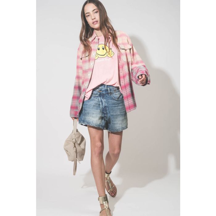 Tee-shirt manches courtes Smiley Have A Nice Day R13 en coton et cachemire rose. Porté de face avec un short en jean crossover bleu. 
