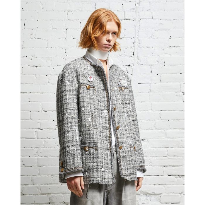 Veste oversized en tweed gris et taches de peinture avec des chaines, épingles à nourrice et badges R13. Porté de profil. 
