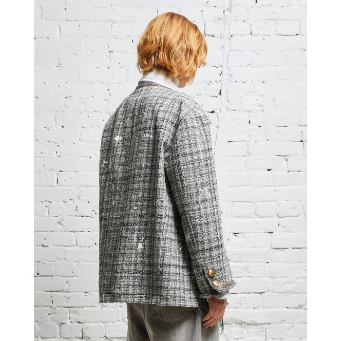 Veste oversized en tweed gris et taches de peinture avec des chaines, épingles à nourrice et badges R13. Porté de dos de profil.