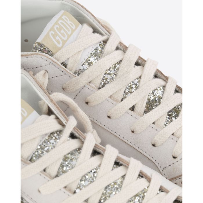 Sneakers Mid Star Golden Goose en cuir blanc, étoile et languette à paillettes argent. Détail des lacets et de la languette à paillettes argentées.