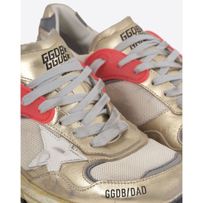 Sneakers Running Dad Golden Goose femme dorée étoile blanche. Détail du passage rouge pour les lacets gris.