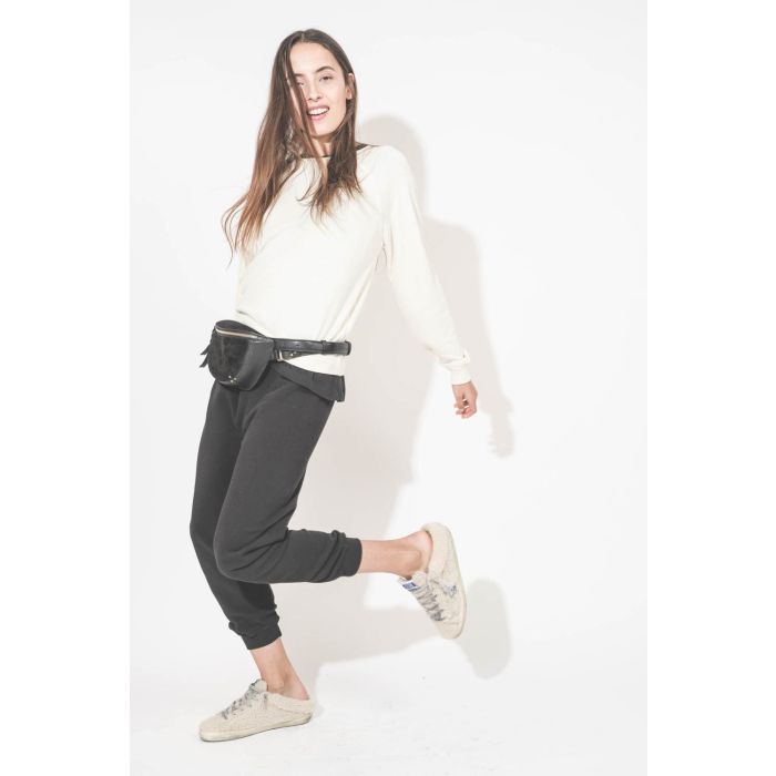 Pantalon de jogging taille basse à nouer sur les hanches resserré en bas bord côte noir The Cropped Sweatpant The Great. Porté de profil avec un sweat-shirt Shrunken écru The Great et des sneakers Super Star sabot en fourrure écur 10757 Golden Goose. Sac 