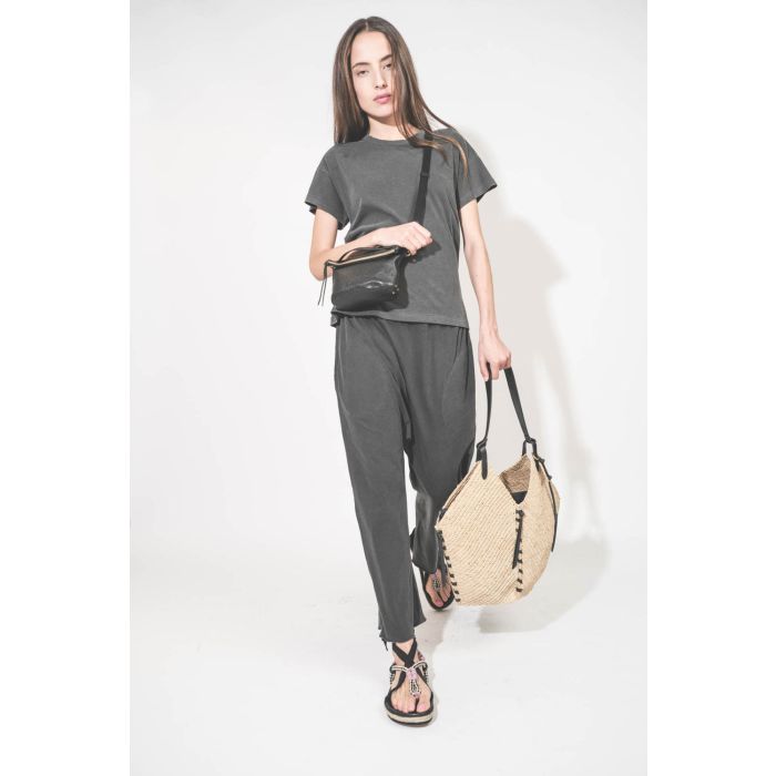 Pantalon sarouel court en jersey noir délavé The Great. Porté de face en marchant avec un tee-shirt manches courtes noir délavé Boxy Crew The Great et des sandales en cordes tressées avec ruban Gypsa noir Isabel Marant. Pochette Lucky en cuir noir avec un