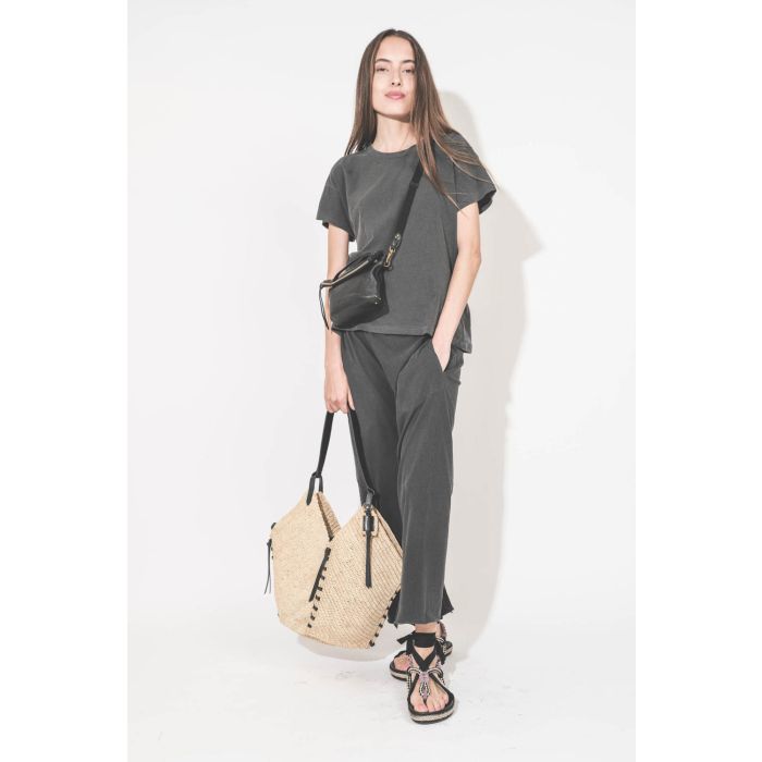Pantalon sarouel court en jersey noir délavé The Great. Porté main dans la poche avec un tee-shirt manches courtes noir délavé Boxy Crew The Great et des sandales en cordes tressées avec ruban Gypsa noir Isabel Marant. Pochette Lucky en cuir noir avec une