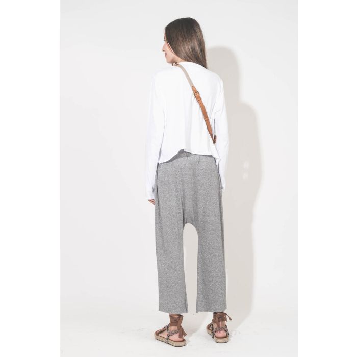 Pantalon sarouel court en jersey gris chiné The Great. Porté de dos avec une tee-shirt court manches longues blanc et des sandales en cordes tressées et ruban beige Gypsa Isabel Marant. Pochette Lucky en cuir suédé caramel portée crossbody avec une sangle