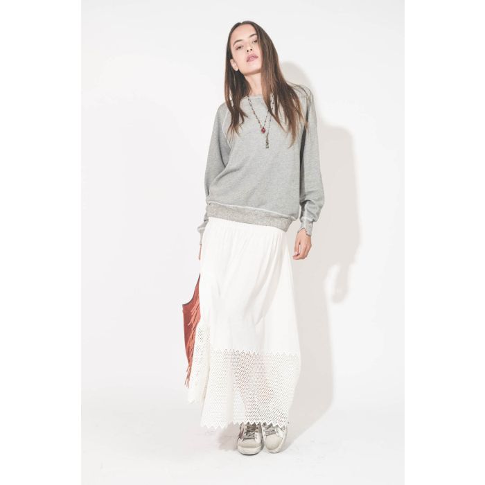 Jupe longue en coton et nid d'abeille placé sur le bas de la jupe blanche The Canary Skirt The Great. Portée de face avec un sweat-shirt gris chiné College The Great et des sneakers Super Star sabot Golden Goose. Cabas à franges en cuir Terracotta Paco Jé